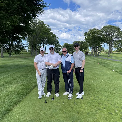 Four golfers posing together on the course during the 2025 Smile Farms Golf Outing.