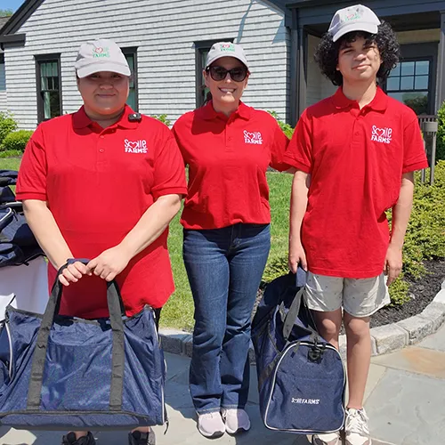 Three Smile Farms team members in red shirts and white caps during the 2026 Golf Outing.